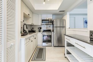 A modern kitchen with white cabinetry, stainless steel appliances, and a built-in oven.