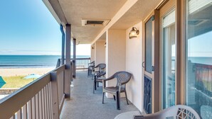Ein Balkon mit Blick auf den Strand, Stühle und ein Tisch.