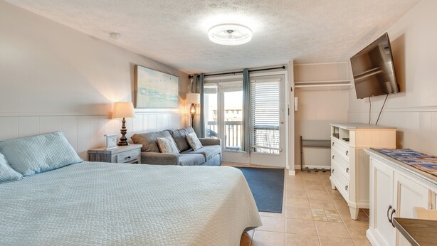 Un dormitorio con cama, sofá, televisión y escritorio.
