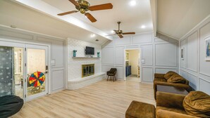 A spacious living room with a fireplace, wooden flooring, and a ceiling fan. - Family Home w/ Patio in Irving: Pets Welcome! (Irving)