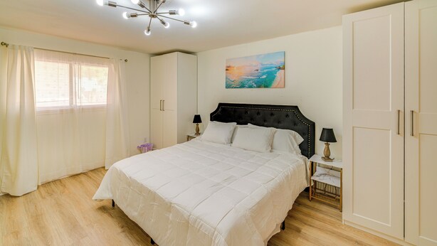 A bedroom with a large bed, a nightstand, a wardrobe, and a ceiling light fixture. - Family Home w/ Patio in Irving: Pets Welcome! (Irving)