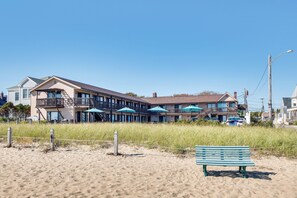 A beachfront hotel with multiple balconies, outdoor umbrellas, and a sandy beach area. - 'beachfront 16' Condo on Old Orchard Beach (Old Orchard Beach)
