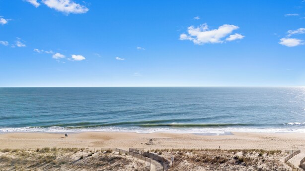 Een strand met een heldere lucht, zandstrand en enkele mensen die lopen.