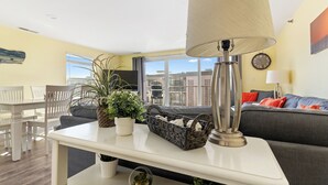 Een moderne woonkamer met een witte tafel, een grijze bank en een groot raam met uitzicht op de stad.
