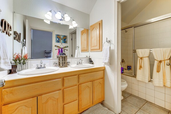 A bathroom with wooden cabinets, two sinks, a mirror, and a shower area. - Neighborhood Beach Access! Soda Springs Getaway (Truckee)