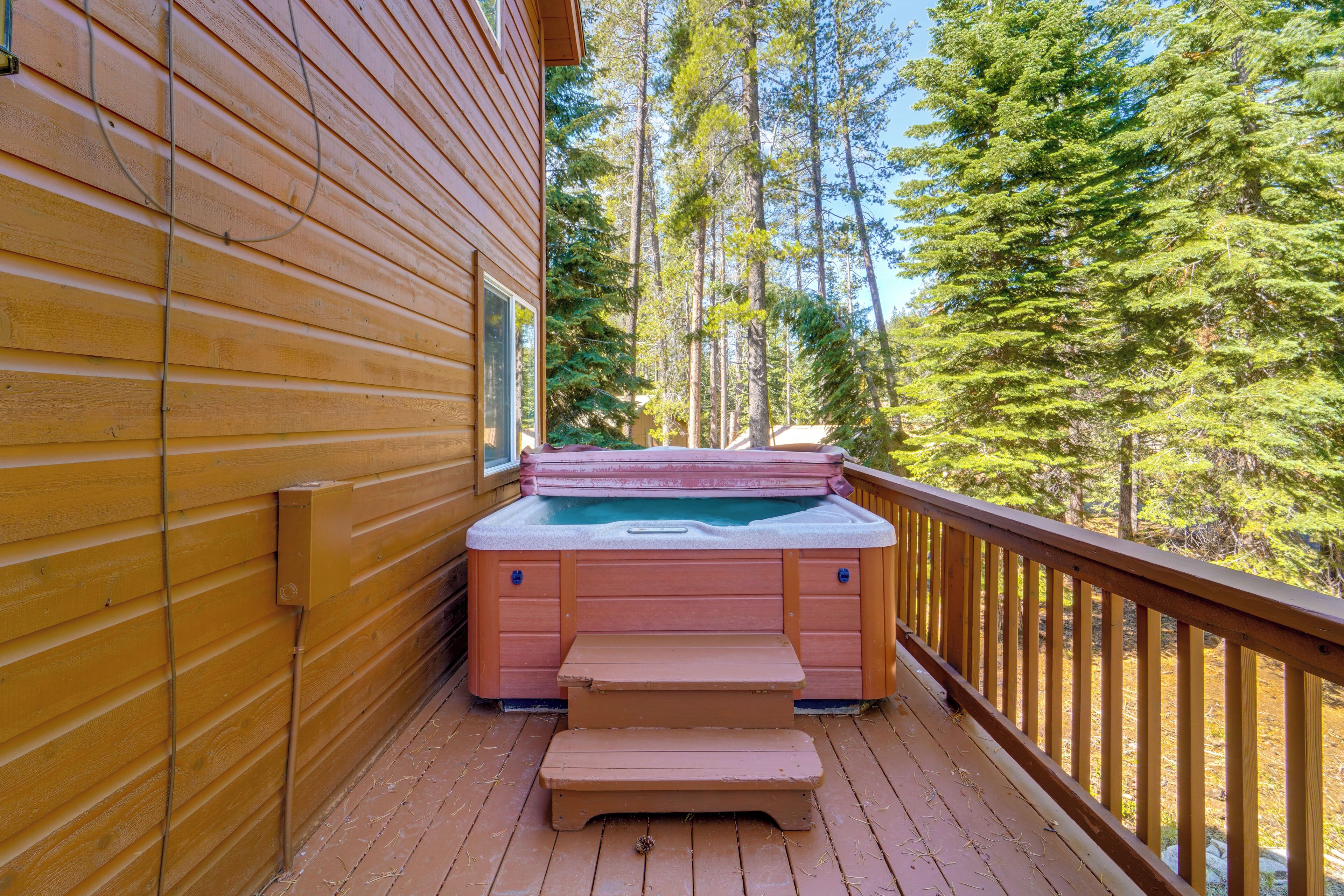 Una terraza de madera con un jacuzzi y una escalera de madera que conduce a otra zona de terraza.