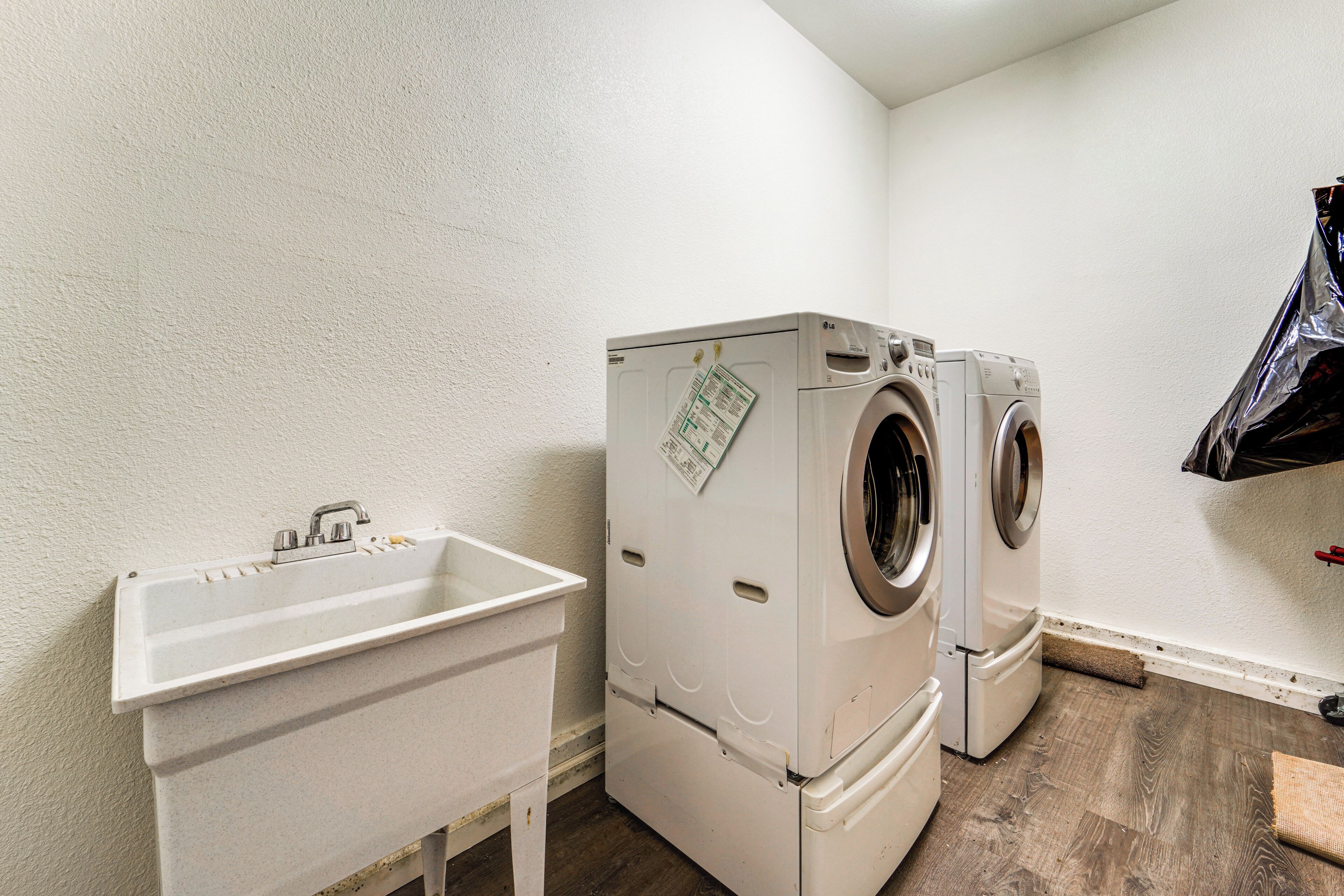 A laundry room with two washing machines, a sink, and a small table.
