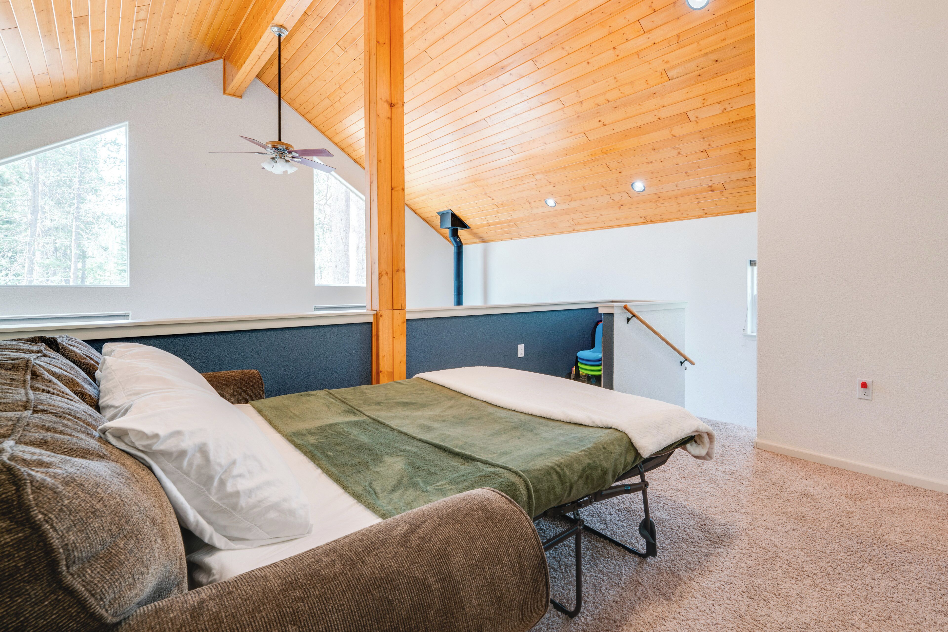 A room with a bed, a chair, a ceiling fan, and a window.