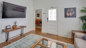 A living room with a flat-screen TV, a wooden coffee table, a sofa, a rug, and a door leading to another room. - Near Oaklawn Casino & Dtwn: 'capone's Hideout' (Hot Springs)