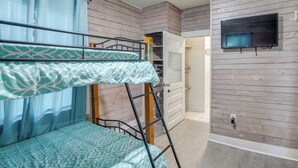 A bunk bed with patterned bedding, a television mounted on the wall, and a wooden door leading to a bathroom. - Near Oaklawn Casino & Dtwn: 'capone's Hideout' (Hot Springs)
