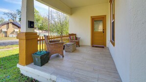 A covered porch with wicker furniture, a wooden door, and a small window. - Near Oaklawn Casino & Dtwn: 'capone's Hideout' (Hot Springs)
