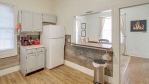 A compact kitchen with white cabinets, a white refrigerator, a coffee station, and a dining area with a wooden table and chairs. - Near Oaklawn Casino & Dtwn: 'capone's Hideout' (Hot Springs)