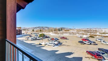 A parking lot with various vehicles, a building with a red facade, and a clear blue sky.