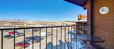 A balcony with a view of a parking lot and distant landscape.