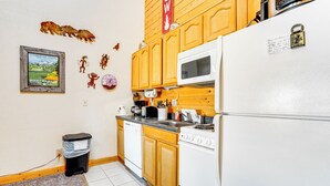 A kitchen with wooden cabinets, a white refrigerator, a microwave, and a stove. There is a trash can and a framed picture on the wall. - 2 Mi to Granby Ranch: Studio w/ Resort Amenities! (Granby)