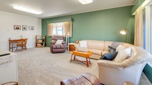 A living room with a beige sofa, a brown leather chair, a wooden coffee table, and a small wooden side table.