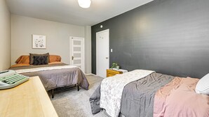 A bedroom with two beds, a desk with a typewriter, and a door. - Patio, Grill & Outdoor Dining: Conrad Home! (Conrad)