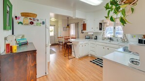A modern kitchen with white cabinets, a wooden countertop, and a hanging plant.