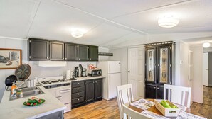 Una cucina compatta con pensili scuri, un frigorifero bianco e un'area pranzo con tavolo e sedie.