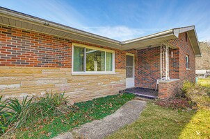 A brick house with a stone foundation, a front porch, and a small garden area.