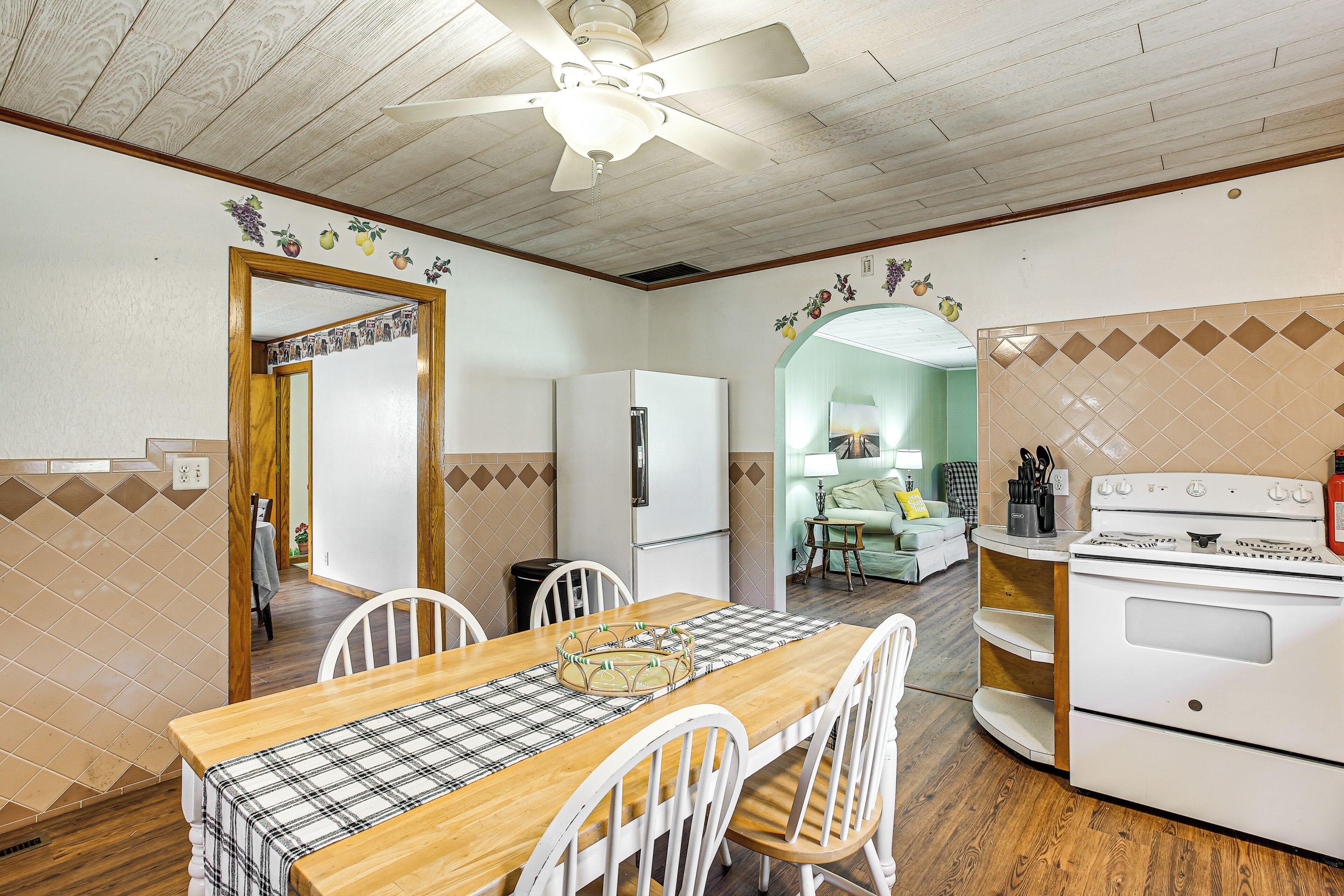 A kitchen with a wooden table, white chairs, a refrigerator, and a stove.