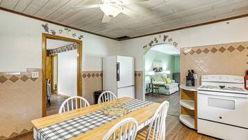 A kitchen with a wooden table, white chairs, a refrigerator, and a stove.