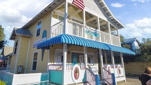 A two-story building with a blue and white striped awning, an American flag, and a sign that reads "Blue Mountain Beach Creamery." - Golf Cart & 4 Bikes! Steps to Pool! Bike to Beach! King Master & 2 Sets of Bunks! ~ Coconut Cottage in Highland Parks on 30A (Santa Rosa Beach)