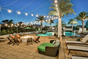 Une terrasse extérieure avec une piscine, des chaises longues et un foyer.