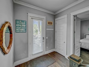 A hallway with two white doors, a wooden bench, a rug, and a wall sign. - Golf Cart & 4 Bikes! Steps to Pool! Bike to Beach! King Master & 2 Sets of Bunks! ~ Coconut Cottage in Highland Parks on 30A (Santa Rosa Beach)