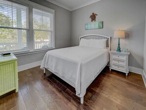 Une chambre à coucher comprenant un lit, une table de chevet, une lampe, une fenêtre et un élément de décoration murale.