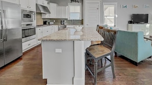 A spacious kitchen with white cabinetry, a granite countertop, and a central island. - Golf Cart & 4 Bikes! Steps to Pool! Bike to Beach! King Master & 2 Sets of Bunks! ~ Coconut Cottage in Highland Parks on 30A (Santa Rosa Beach)