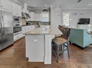 A spacious kitchen with white cabinetry, a granite countertop, and a central island.