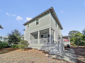 A two-story house with a front porch and a covered patio area.