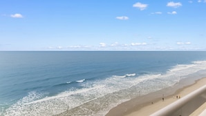 A beach with waves, a clear sky, and a few people.