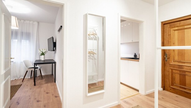 Een compacte leefruimte met een eethoek, een klein kitchenette en een houten deur.