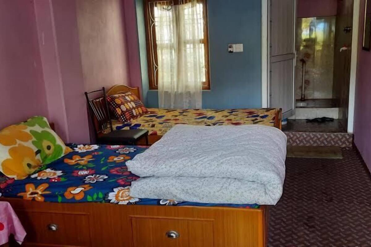 A bedroom with two beds, a window with curtains, and a door leading to a balcony.