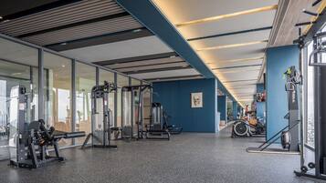 A gym with various exercise machines, glass walls, and a blue accent wall.