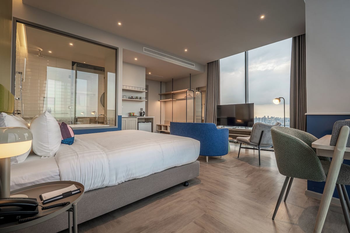 Une chambre d’hôtel moderne équipée d’un grand lit, d’un bureau, d’une chaise et d’un téléviseur.