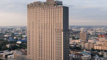 Un palazzo alto con la scritta "RAMKHAMHENG HILLS QUARTER" sulla facciata, circondato da altri edifici e un cielo sereno.