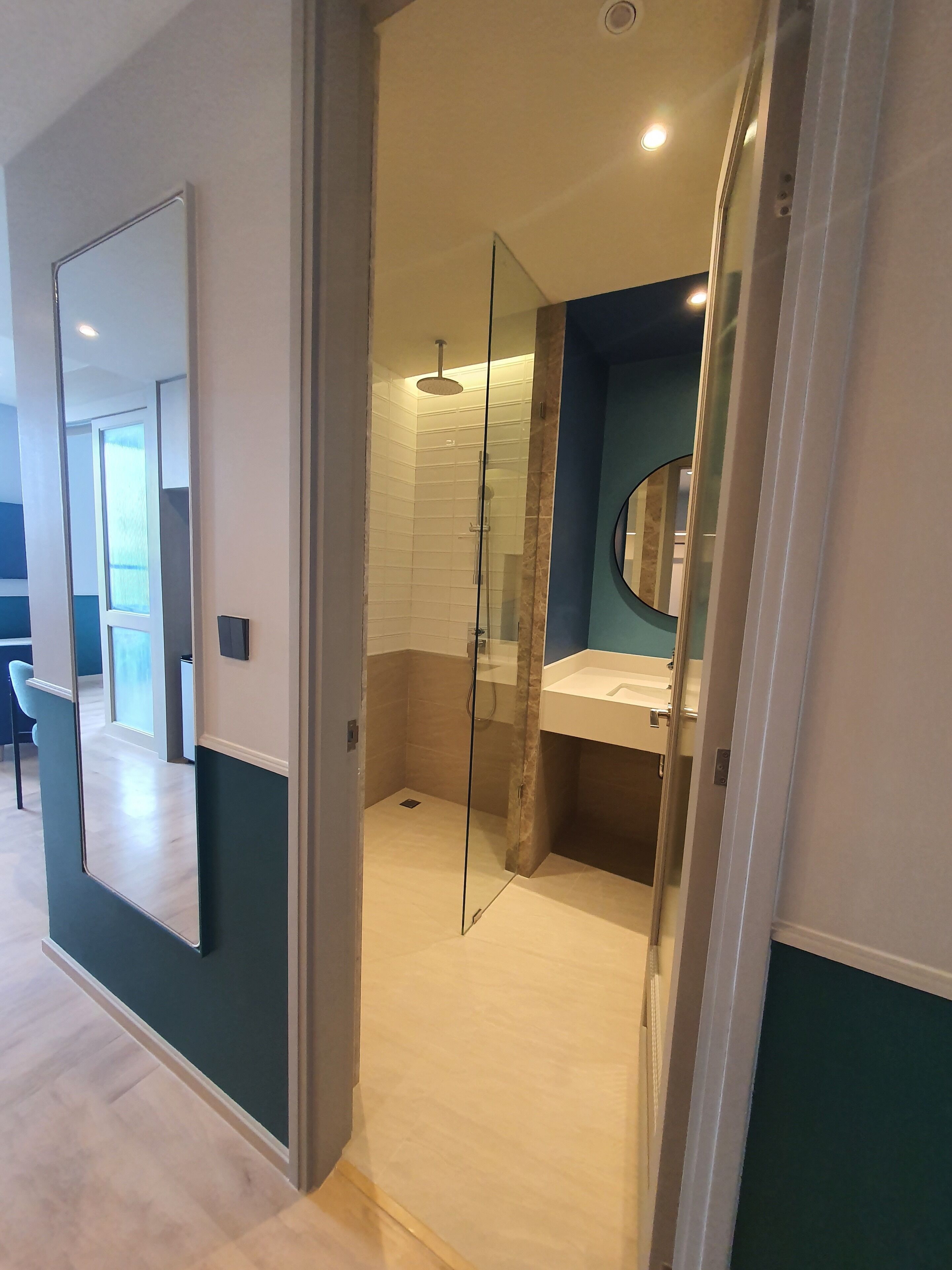 A modern bathroom with a glass shower enclosure, a sink with a mirror, and a visible toilet.