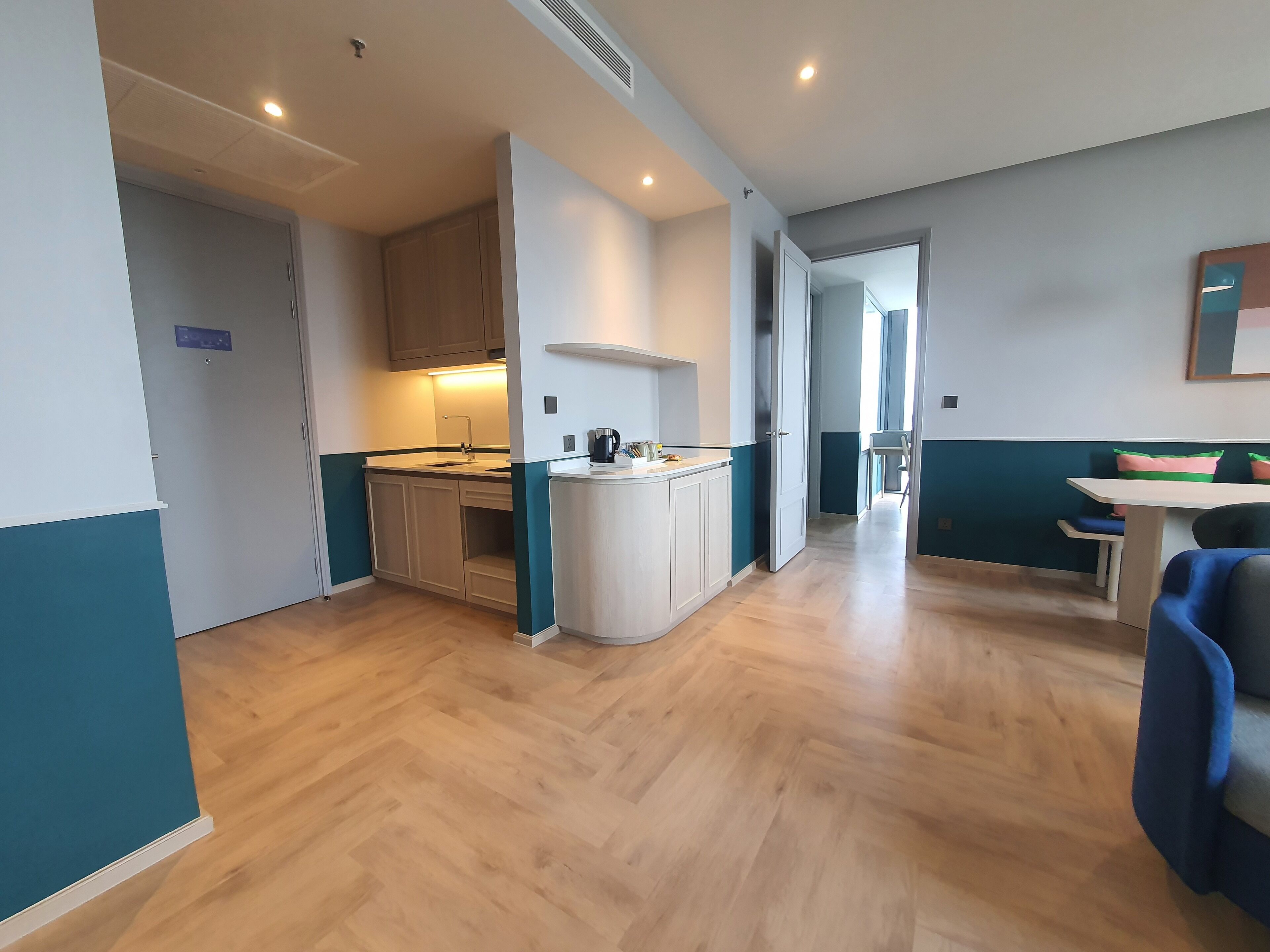 A compact kitchen with a sink, cabinets, and a coffee maker. There is a dining area with a table and chairs.