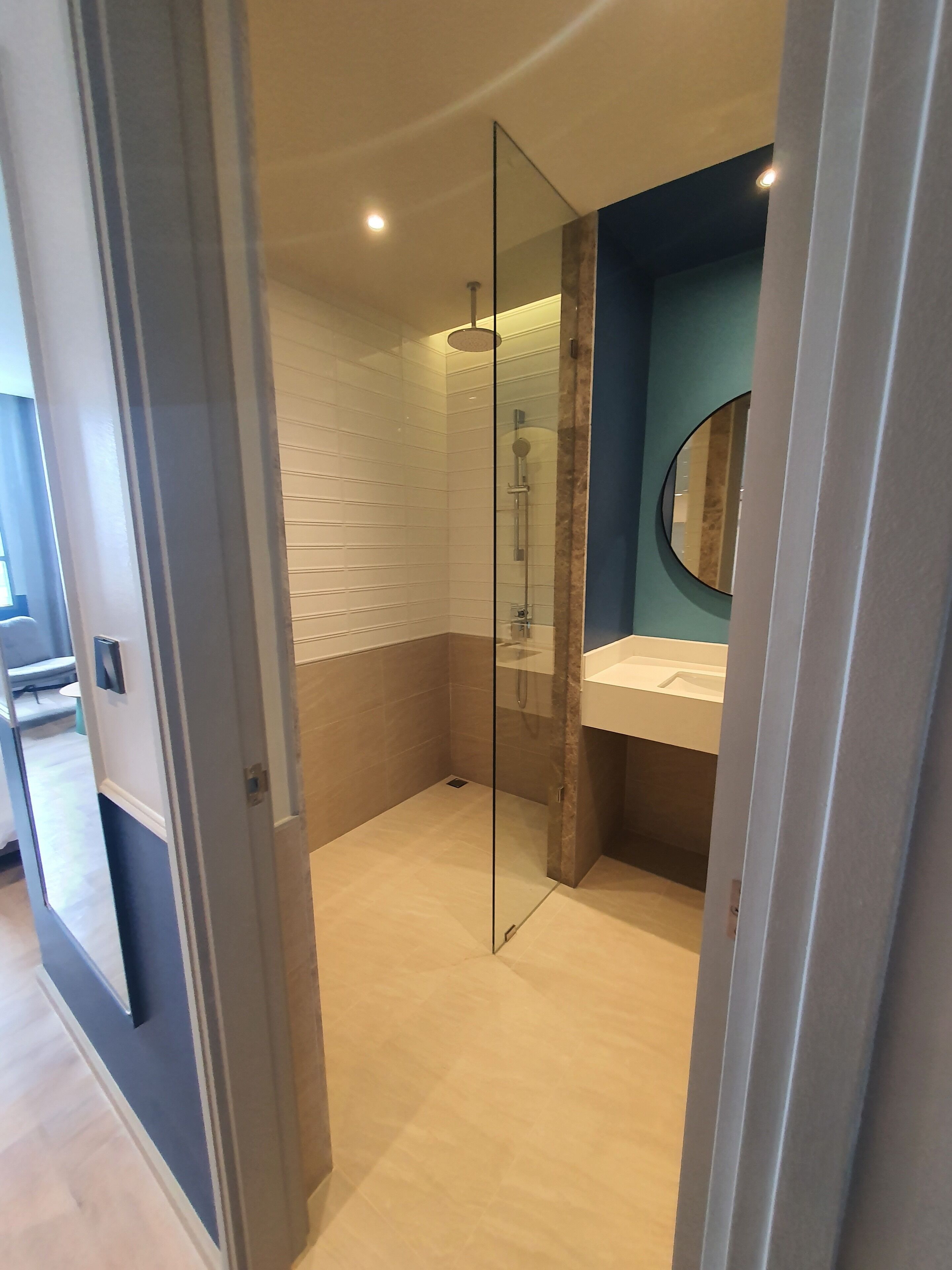 A modern bathroom with a glass shower enclosure, a sink with a mirror, and a tiled floor.