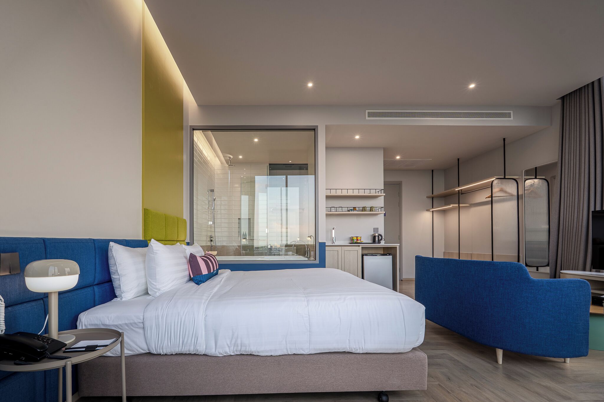 Ein modernes Hotelzimmer mit einem großen Bett, einem Schreibtisch, einem Sessel und einem Fernseher.