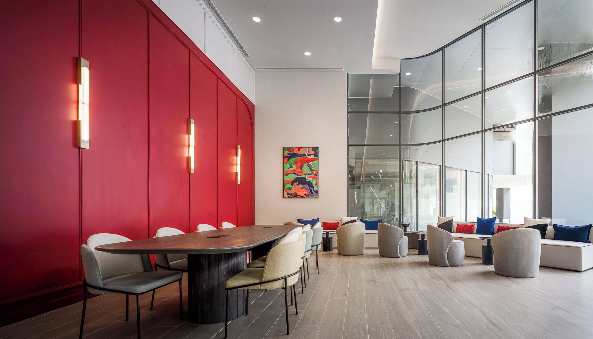 A modern conference room with a red accent wall, a large table, and comfortable seating.