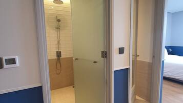 A modern bathroom with a glass shower enclosure, a visible showerhead, and a digital thermostat on the wall.