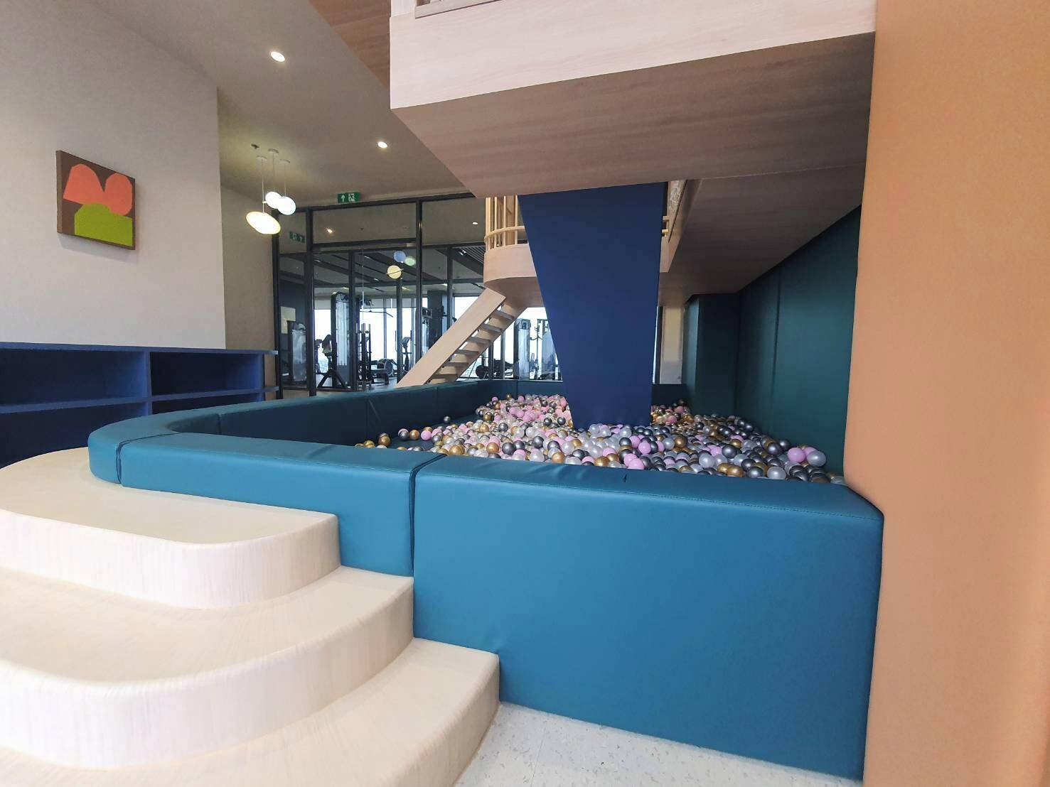 A modern interior with a blue seating area and a ball pit.