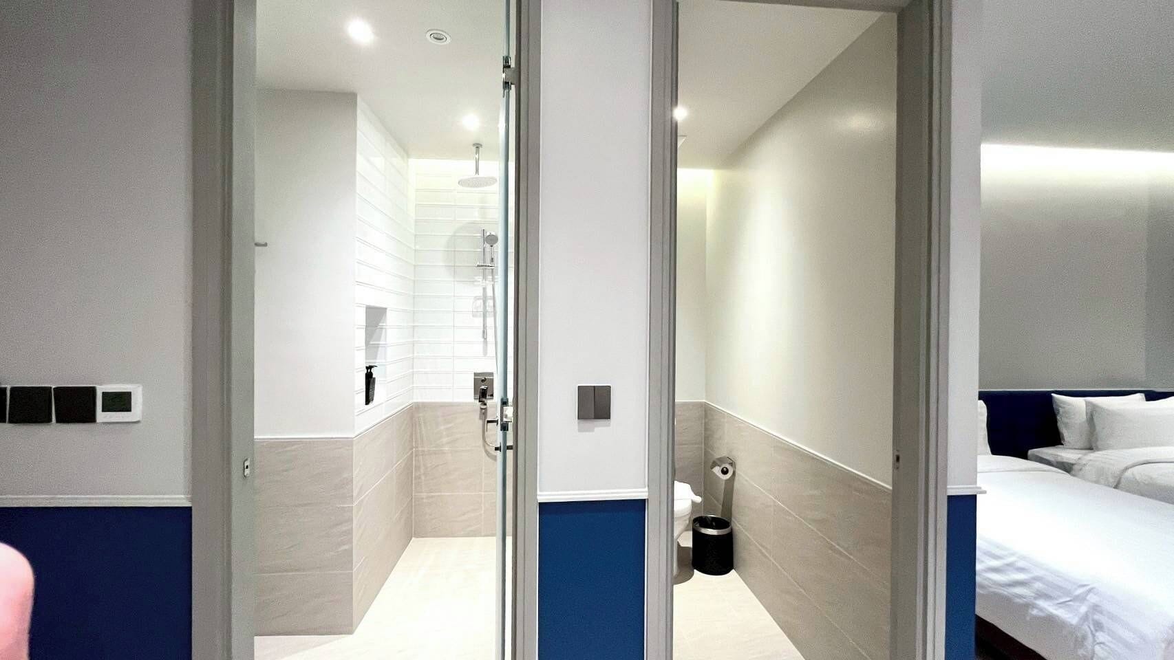 A modern hotel room with a shower, toilet, and bed.