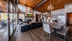 A spacious living area with a large wooden ceiling, a stone fireplace, and a modern kitchen with stainless steel appliances. - Treehouse at the Wilderness Club (Eureka)
