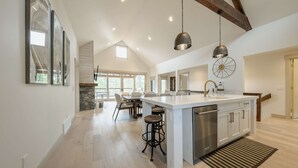 A spacious kitchen with a large island, pendant lighting, and a stone fireplace. - Wilderness Club Haven for 12! (Eureka)