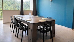 A dining area with a long table, black chairs, and a blue accent wall. - Mount Minar (Devikolam)